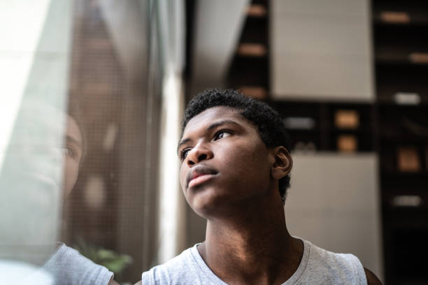 Teenager boy looking through the window at home